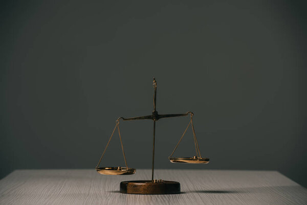 empty scales of justice on wooden table on grey 