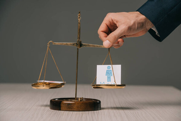 cropped view of businessman with scales of justice and male signs, gender stereotypes concept 