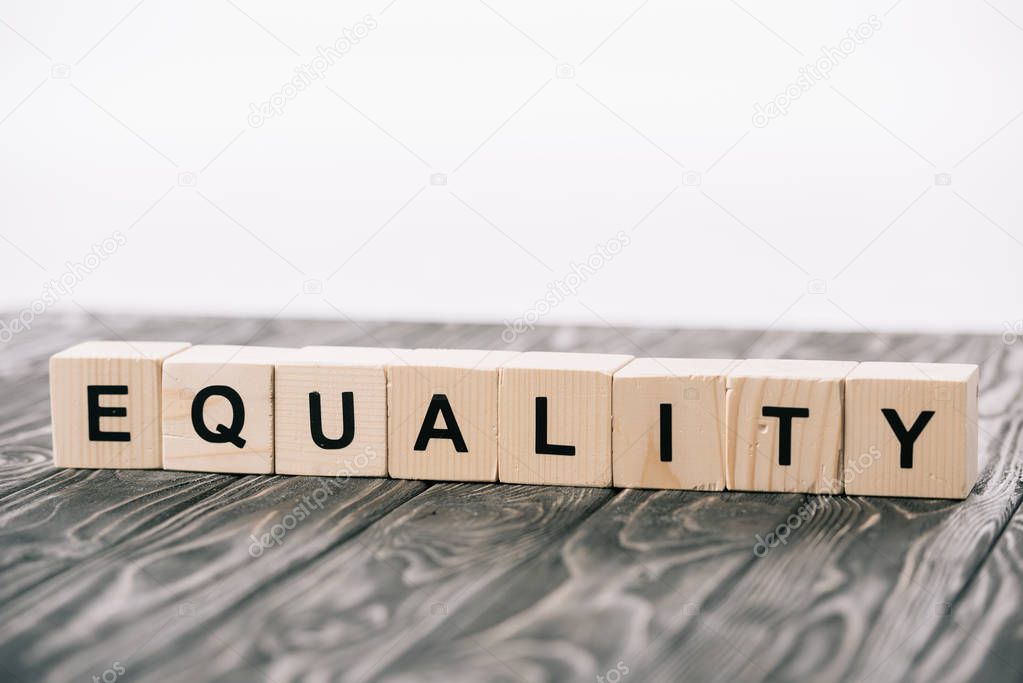 equality lettering made from alphabet cubes on wooden table on white