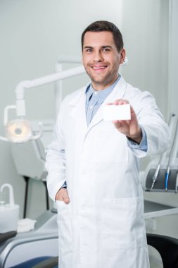 elle cebinde duran ve boş kartı holding neşeli diş hekimi 