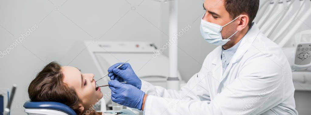 dentist in mask and latex gloves examining teeth of woman in dental clinic