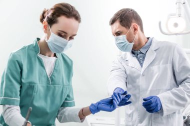erkek diş hekimi diş enstrüman maskeli kadın meslektaşım vermek