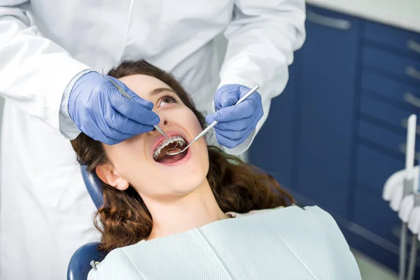 Visão Recortada Dentista Examinando Mulher Aparelho Com Boca Aberta — Fotografia de Stock