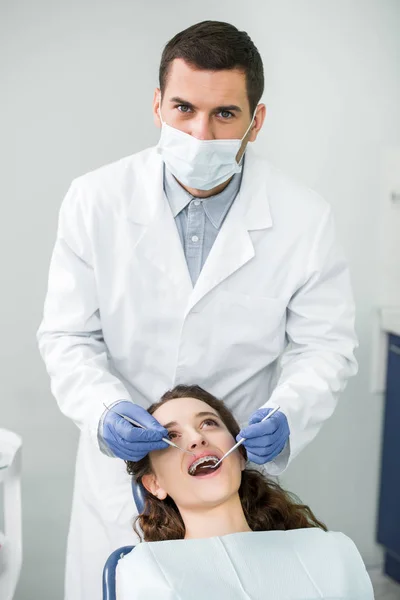 Dentista Máscara Luvas Látex Examinando Mulher Aparelho Com Boca Aberta — Fotografia de Stock