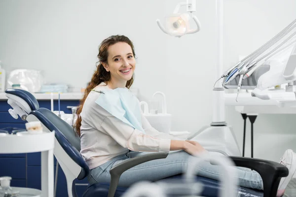 Vrolijke Vrouw Met Accolades Tanden Glimlachend Zittend Een Stoel Tandheelkundige — Stockfoto