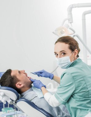 dişçi diş Kliniği hastada ile çalışırken diş matkap tutan maskeli