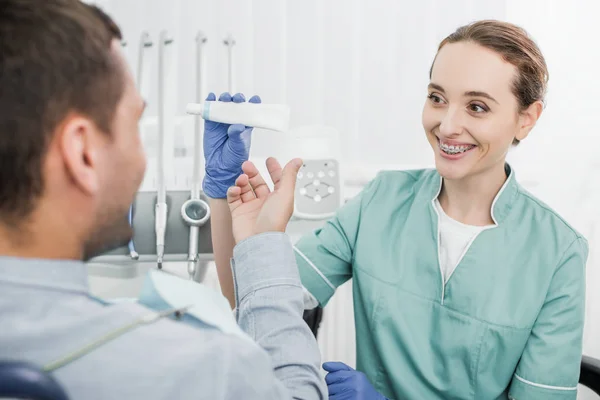 Foco Seletivo Dentista Atraente Segurando Pasta Dentes Perto Paciente — Fotografia de Stock