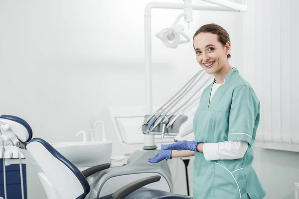 Attraente Dentista Con Bretelle Sui Denti Sorridente Gesticolare Clinica Dentale — Foto Stock