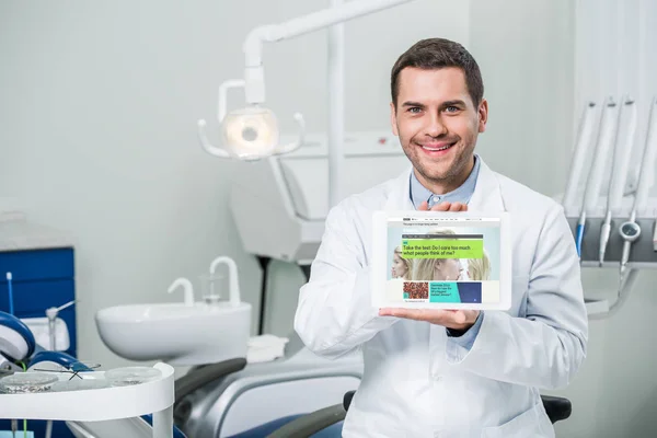 愉快的牙医拿着数字平板电脑与 Bbc 应用程序在屏幕上的牙科诊所 — 图库照片