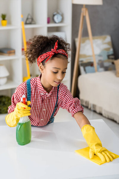 adorable african american child cleaning table with yellow rag