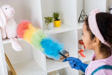güzel bir Afro-Amerikan çocuk toz alma raf ünitesi ile çok renkli toz bezi