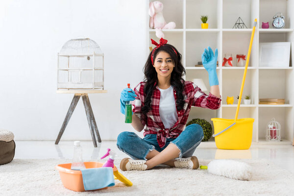 cheerful african american woman in plaid shirt sitting in lotus pose and showing ok sign