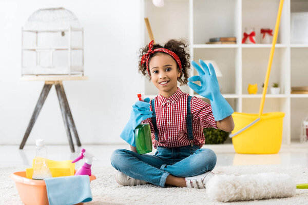 cute african american kid with cleaning supplies showing ok sign