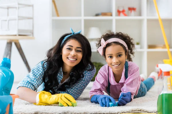 Lächelnde Afroamerikanerin Und Tochter Hellen Gummihandschuhen Auf Teppich Liegend — Stockfoto