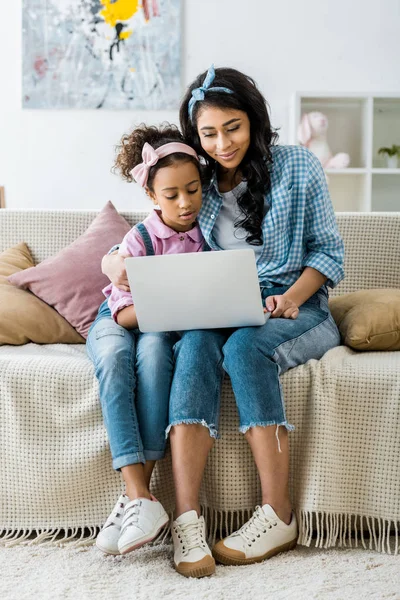 집에서 소파에 앉아있는 노트북을 귀여운 자녀와 아프리카계 미국인 어머니 — 스톡 사진