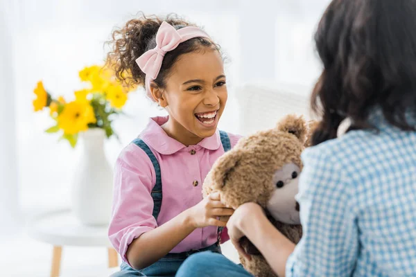 Laughing African American Child Holding Teddy Bear While Sitting Sofa — Stock Photo, Image
