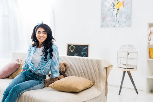 beautiful african american woman sitting on sofa at home