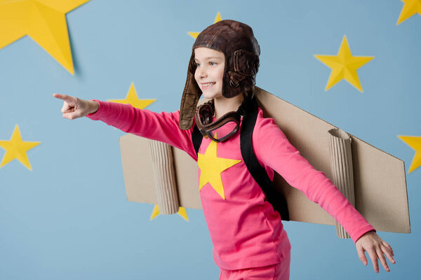 Happy child in flight helmet having fun on blue background with stars