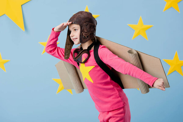 Cute child in flight helmet posing on blue starry background