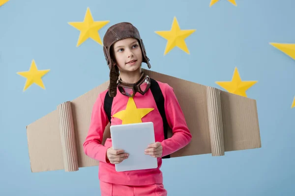 梦幻般的孩子与纸板翅膀拿着数字平板电脑在蓝色背景与星 — 图库照片