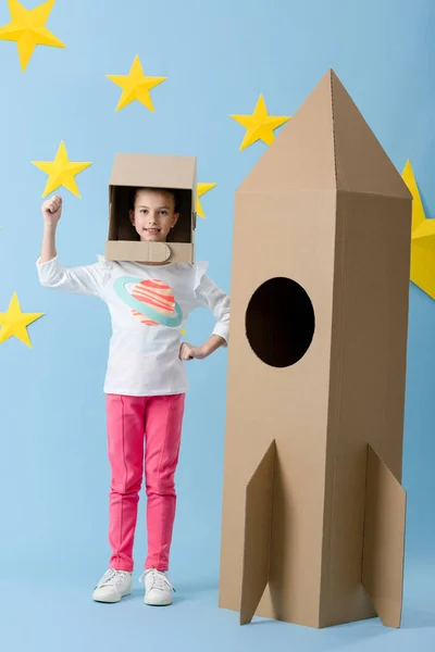 Criança Inspirada Capacete Gesticulando Perto Foguete Papelão Fundo Estrelado Azul — Fotografia de Stock