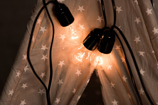 Wigwam with luminous bulbs on dark background