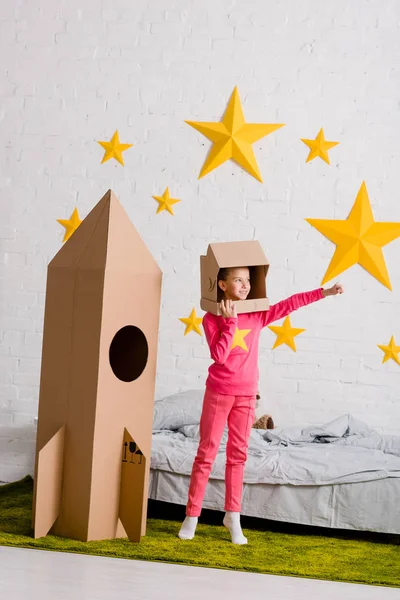 Ganzkörperansicht Eines Kindes Mit Papphelm Das Neben Einer Rakete Schlafzimmer — Stockfoto