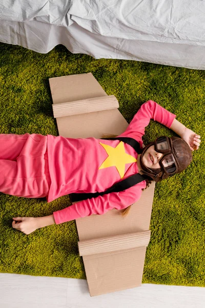 Vista Superior Criança Adorável Com Asas Papelão Deitado Tapete Verde — Fotografia de Stock