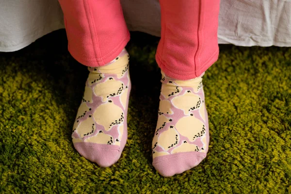Partial view of child in funny socks standing on green carpet