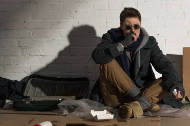evsiz bir adam çöp dökümü üzerinde otururken Sigara İçilmeyen