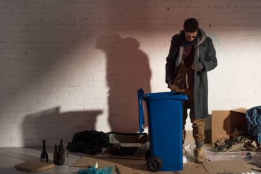 evsiz adam çöp tarafından çevrili Çöp konteyner yanında ayakta