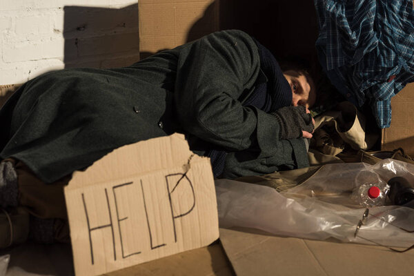 depressed homeless man lying on cardboard on rubbish dump