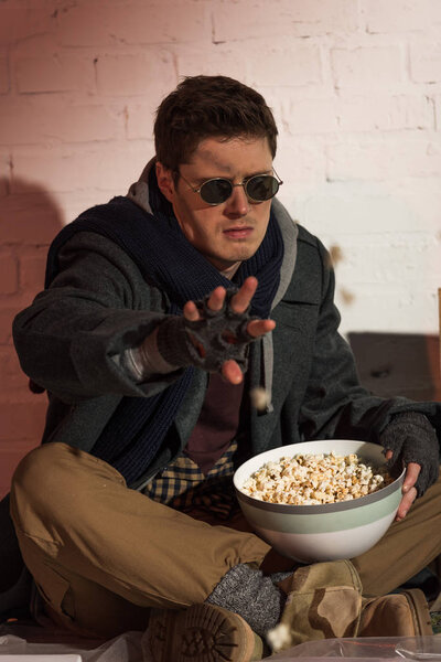 angry homeless man throwing popcorn from bowl at camera