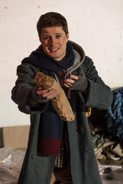 homeless man holding bread baguette in stretched hand