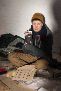 depressed homeless man sitting near cardboard card with 
