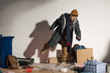 angry homeless man kicking cardboard box with garbage