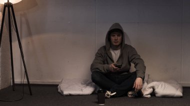 karanlık odada katta düzenlenmiş şişme otururken smartphone kullanarak adam