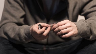 selective focus of man holding smoking pipe and pack of marijuana clipart