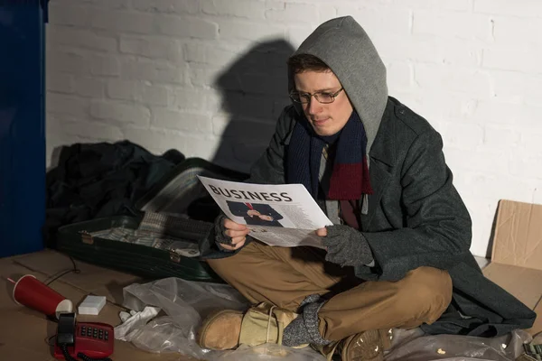 ホームレスはゴミ捨て場に座って新聞を読んで — ストック写真