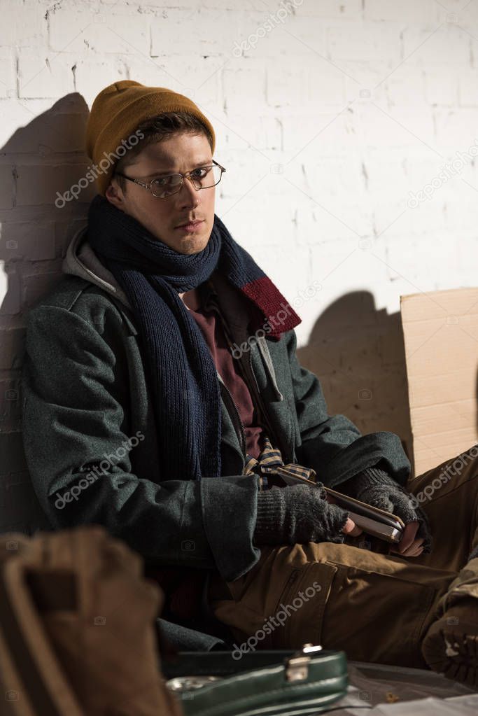 homeless man in glasses sitting on rubbish dump