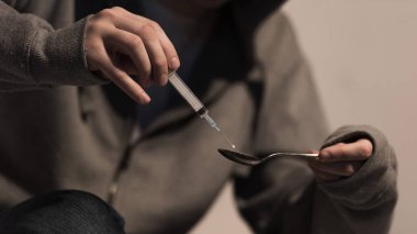 selective focus of addict man filling syringe with heroin clipart
