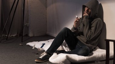 keş adam sigara esrar sigara beyaz yatak katta oturan haddelenmiş