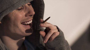 addict man under drug influence holding rolled marijuana cigarette clipart