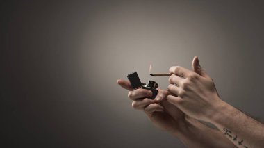 erkek aydınlatma kısmi görünümü gri arka plan üzerinde Esrar sigara haddelenmiş