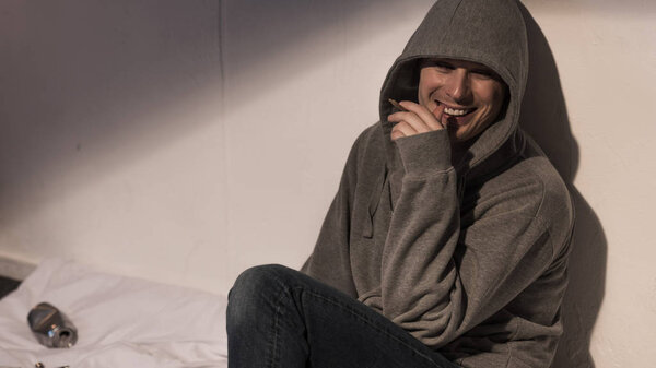 junkie man smoking and laughing under influence of narcotic