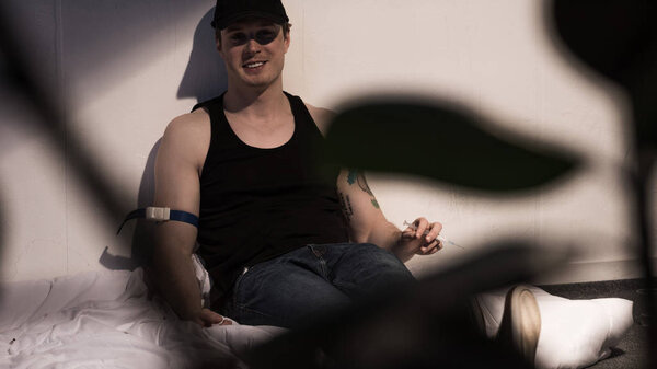 selective focus of junkie man smiling under influence of narcotic