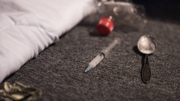selective focus of syringe and spoon with heroin on floor