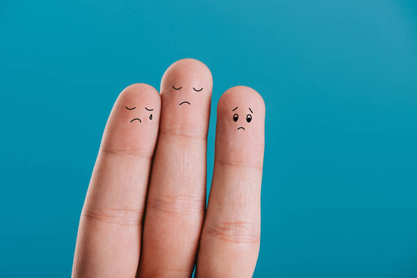 cropped view of upset human fingers crying isolated on blue