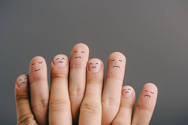 partial view of upset human fingers with closed eyes isolated on grey