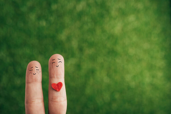 cropped view of happy couple of fingers with heart for valentines day on green